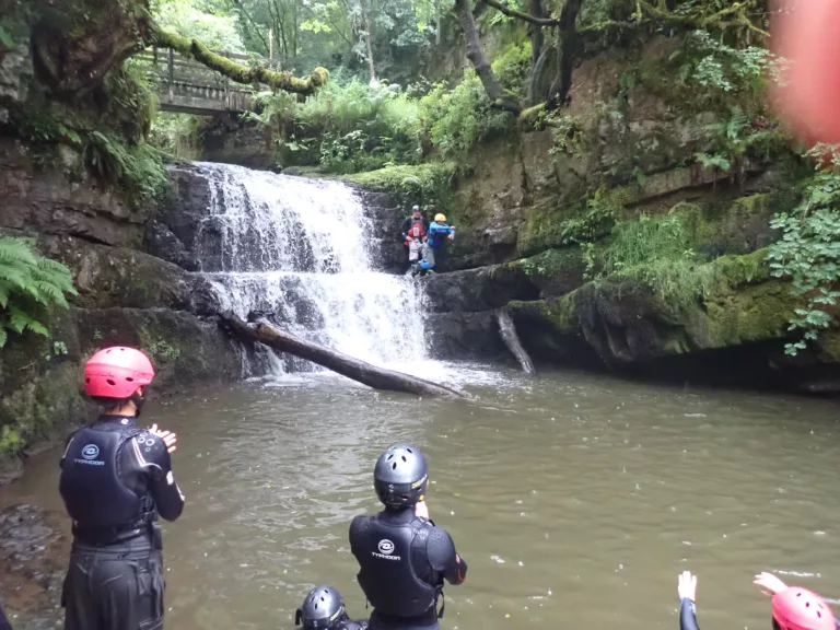 Group of scouts in waterfall plunge pool and crossing waterfall