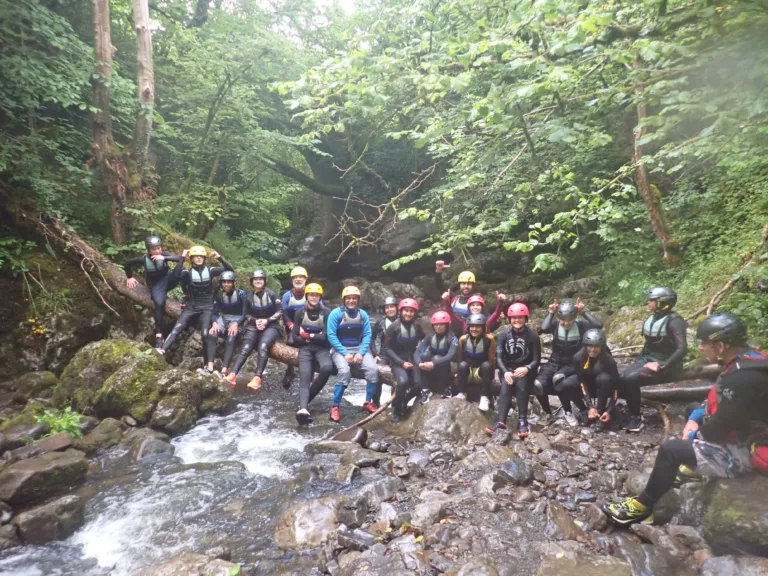 Youth group sat on log across a river in a gorge in the Brecon Beacons, South Wales