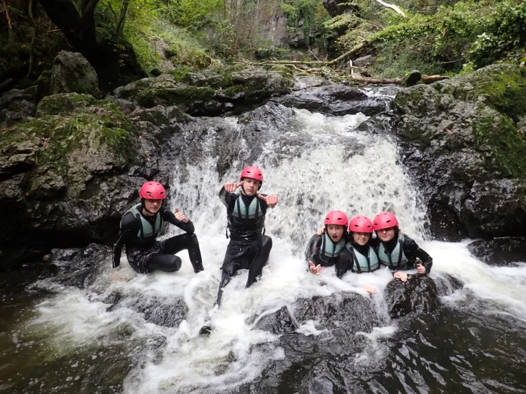 Group say in a waterfall on the Brecon Beacons National Park on a gorge scrambling activity