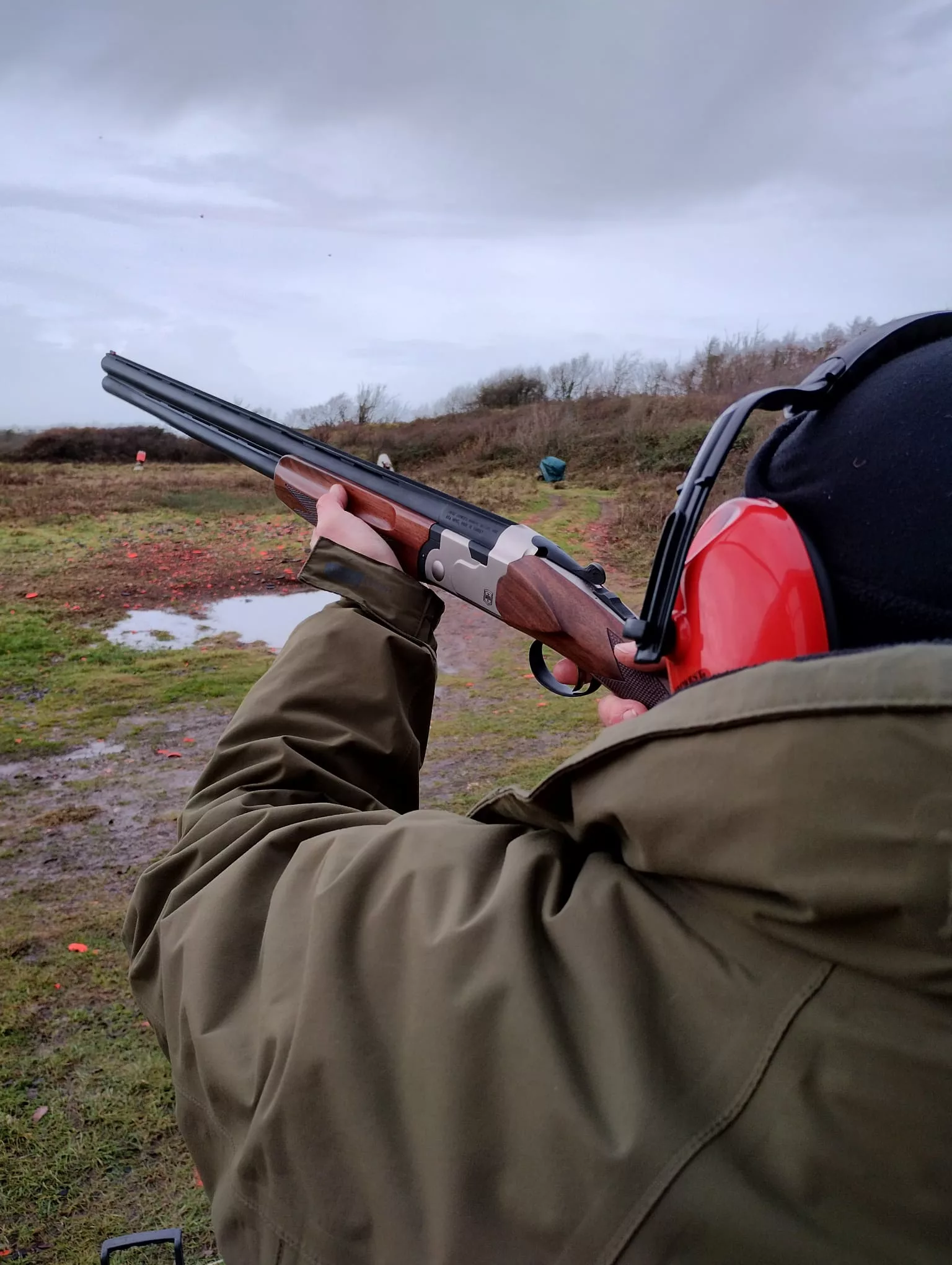 Man taking aim with a shotgun during a clay pigeon shooting activity